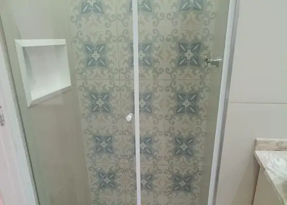 Box de abrir incolor com perfil branco e ladrilho hidráulico azul, na Vila Olímpia