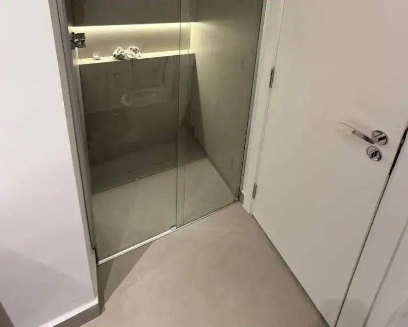 Box de correr em vidro fumê com perfil prata e nicho iluminado, nos Jardins