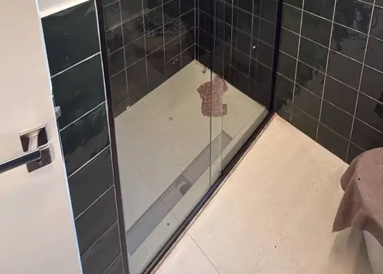 Box de correr com perfil escuro, azulejo verde e nicho com LED, em Moema