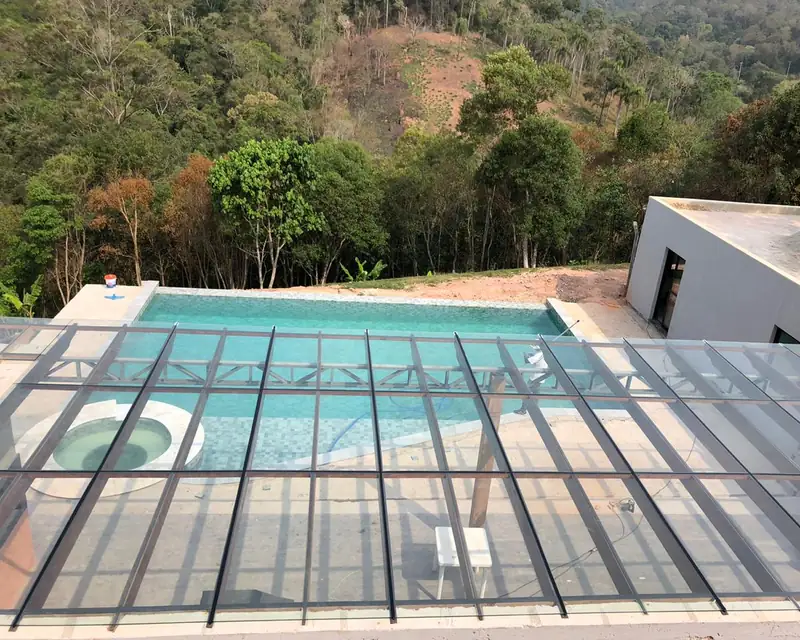 Cobertura de vidro sobre piscina com a serra ao fundo