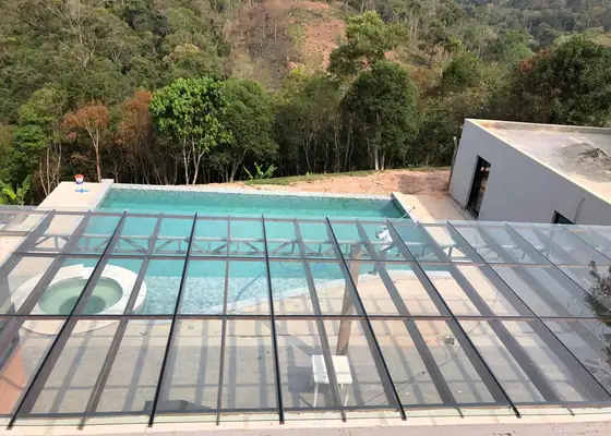 Cobertura de vidro laminado sobre piscina com a serra ao fundo, obra da PS do Vidro