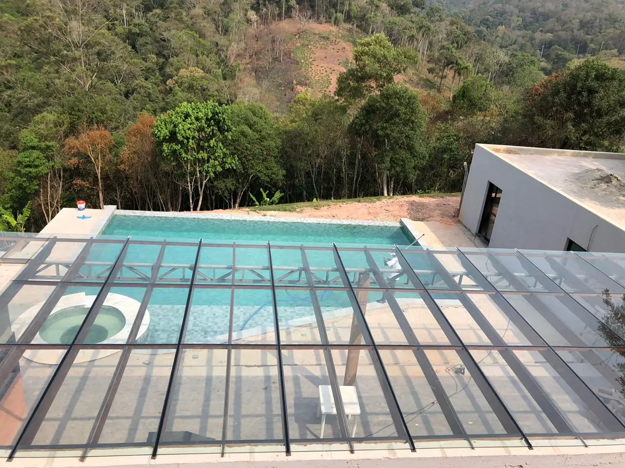 Cobertura de vidro sobre piscina com a serra ao fundo