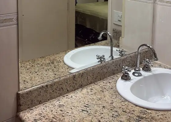 Espelho bisotado sobre bancada de granito em banheiro, em Moema