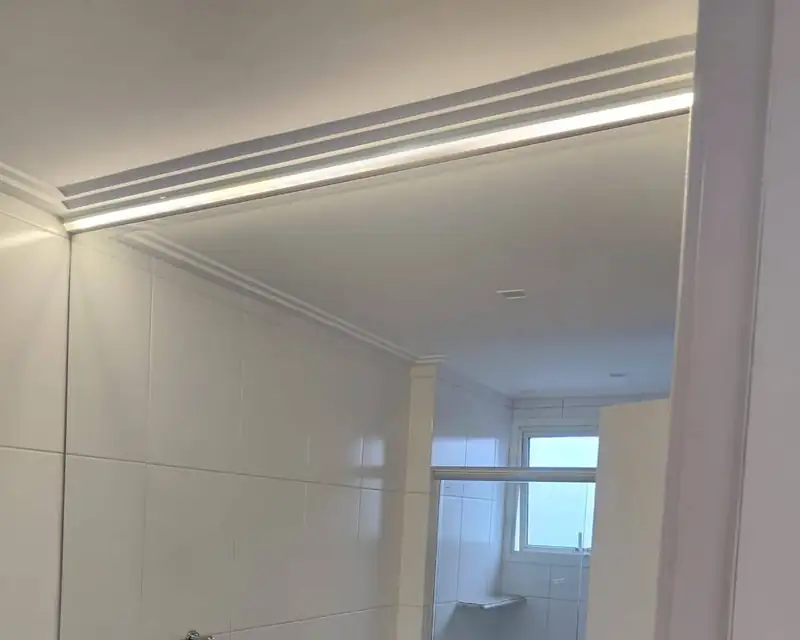 Espelho até o forro com sanca iluminada sobre bancada de granito, no Brooklin