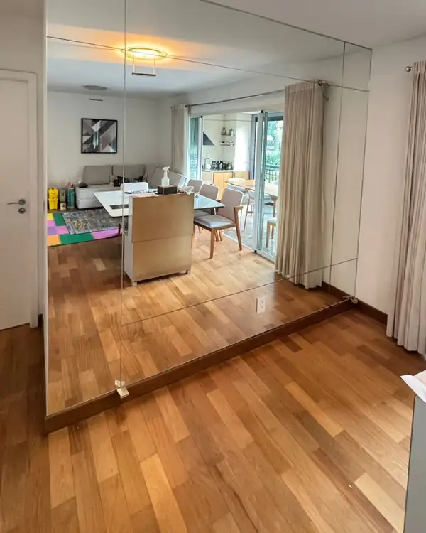 Parede de espelho ampliando a sala, em Moema