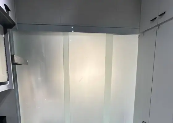 Porta de correr de vidro jateado entre a cozinha e a lavanderia, em Moema