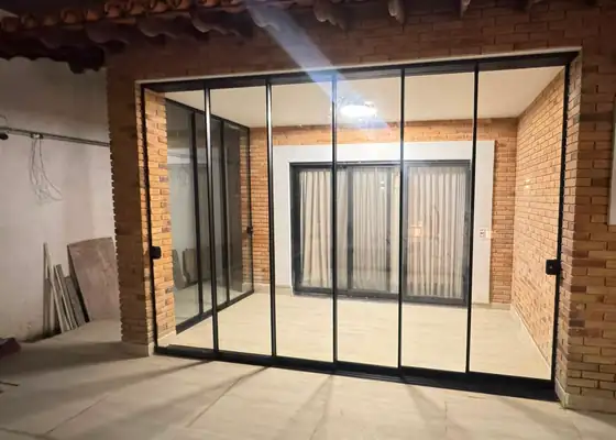 Portas de correr com perfil preto e parede de tijolinho, obra da PS do Vidro
